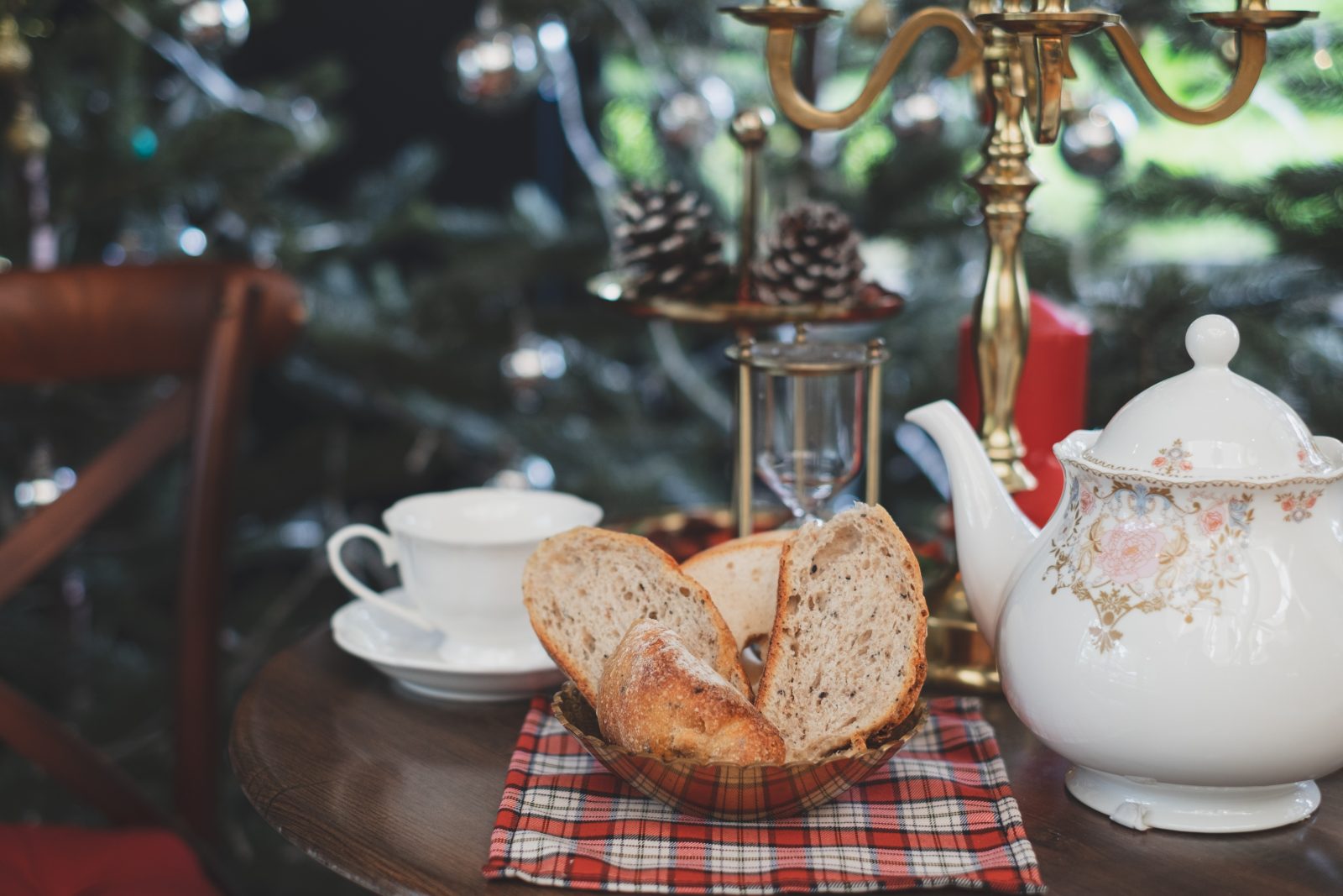 Christmas table setting with a freshly baked sliced festive cake with with vintage teapot, Concpet of christmas table set up with a lit candle at the background. Tea time and afternoon tea.